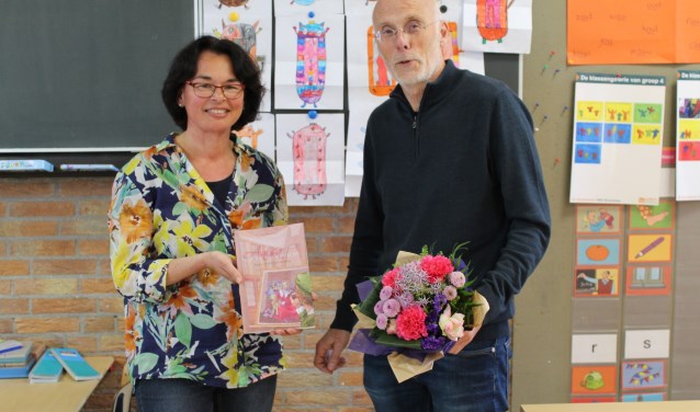 Elly Doornbosch overhandigt het boek aan directeur Cor Both en hij geeft bloemen aan Elly.