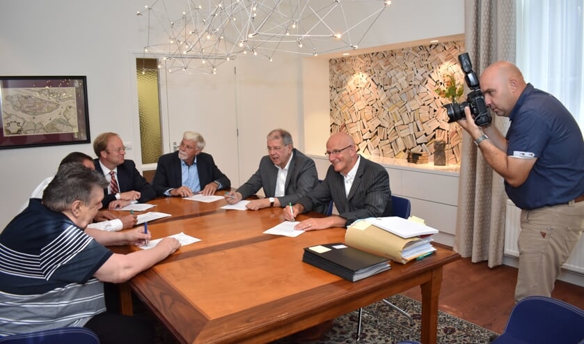 De fotograaf legt vast hoe de bestuurders hun handtekening zetten.