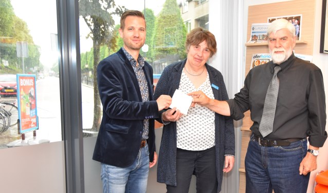 Wim Eijbers, voorzitter van de afdeling Alzheimer Nederland overhandigt de stickers aan de beide filiaalhouers, Meik de Raadt en Jasper Pieterse.