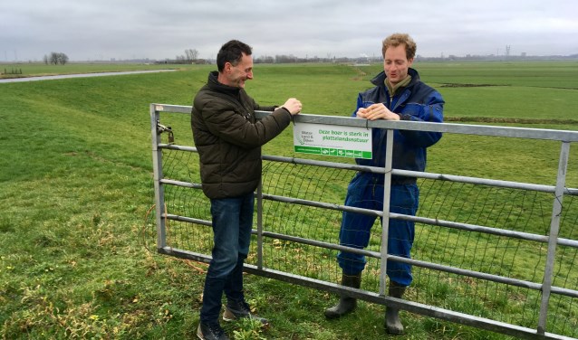 Het eerste bordje wordt opgehangen door voorzitter Sjaak Hoogendoorn en boer Jelle Verbeek.