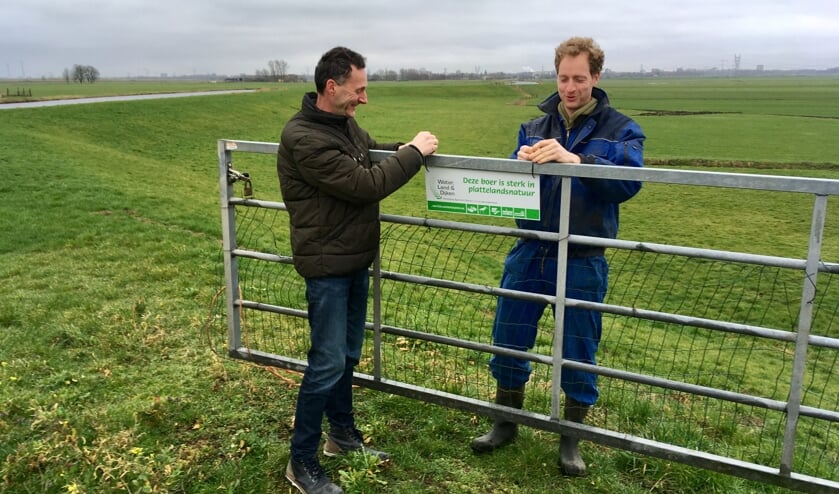 Het eerste bordje wordt opgehangen door voorzitter Sjaak Hoogendoorn en boer Jelle Verbeek.
