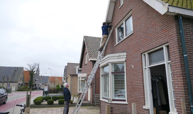 Arjan van Poecke hangt huiszwaluwnest op aan huis in de Kerkbuurt.