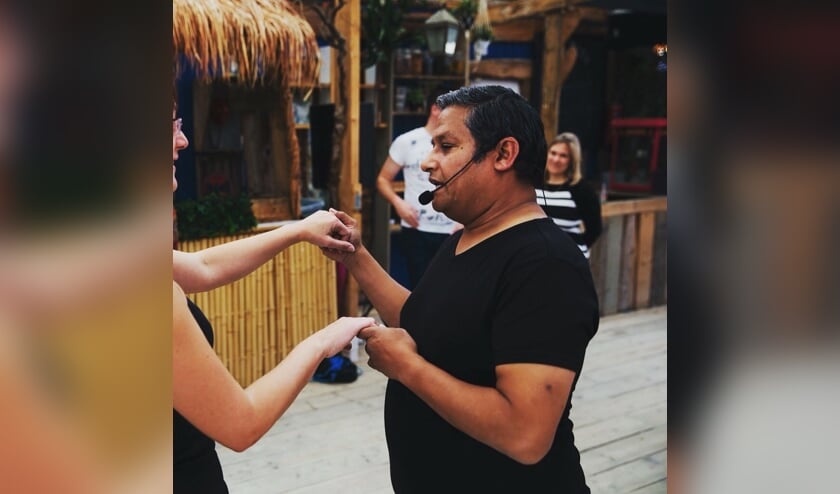 Docent leert deelnemer de passen van de Salsa.