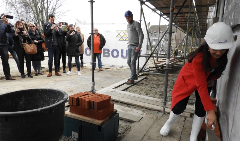 Bewoners maken foto's van de eerste steenlegging door de wethouder.