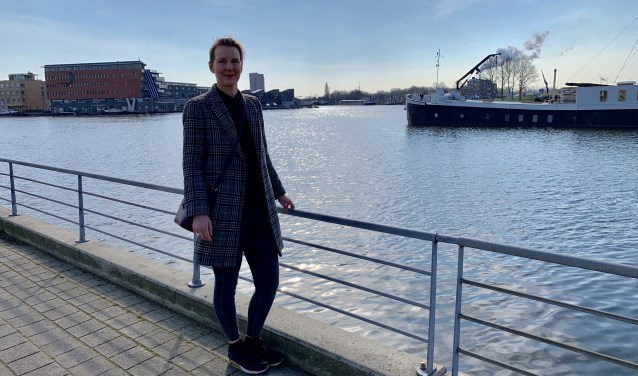 Mede-organisator Fleur Pastoors bij de toegang van Zaaneiland met op de achtergrond het schip van een van de deelnemers.