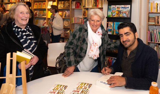 De auteur gaat graag in op het verzoek van Wienny Reuser (midden) om iets in het boek te schrijven. Links Annemiek Scheepers, de vriendin van Wienny.