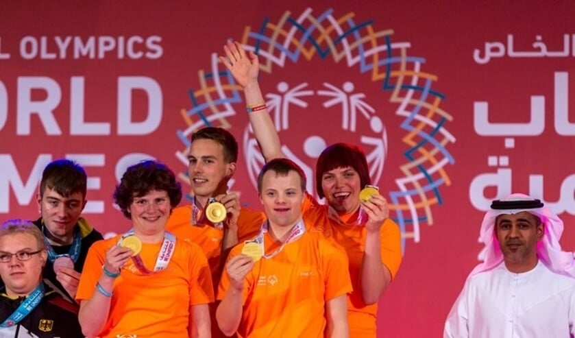 René, tussen zijn teammaatjes, laat zijn gouden medaille zien.
