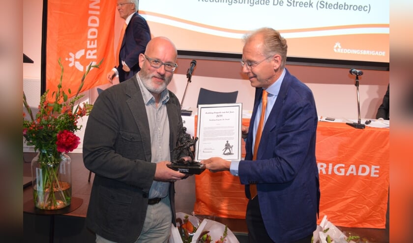 Voorzitter Bob Koelman neemt de trofee Reddingsbrigade van het Jaar in ontvangst.
