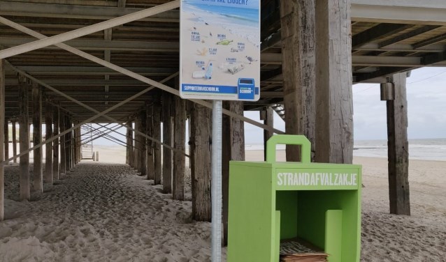 Speciale houders met papieren afvalzakjes neergezet bij de strand etablissementen