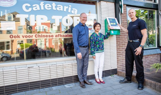 Vlnr: directeur Hans van den Berg van Tata Steel, de eigenaresse van Tip Top en brandweervrijwilliger Rob Martens staan bij de AED.
