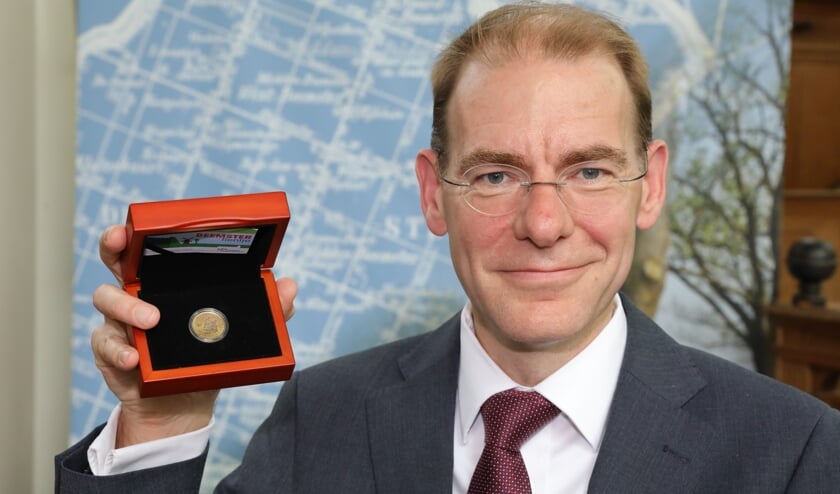 Staatssecretaris Menno Snel met de herdenkingsmunt.