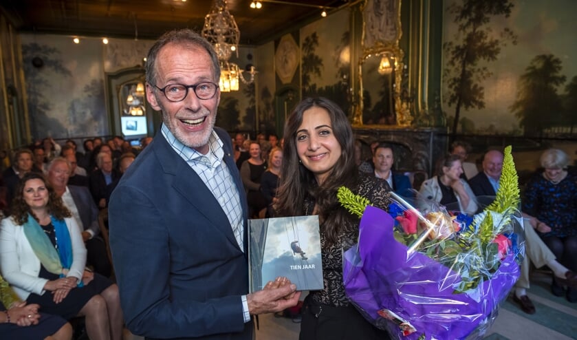 Auteur Ed Pielkenrood overhandigt het eerste exemplaar van het jubileumboek van De Zaan – Zaandijk aan wethouder Songül Mutluer van Zaanstad.
