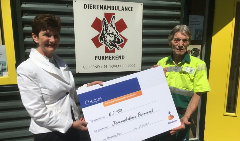 Pim Langereis van de Dierenambulance krijgt de cheque van de afscheid nemende Lea Sterenborg-Pinxt.