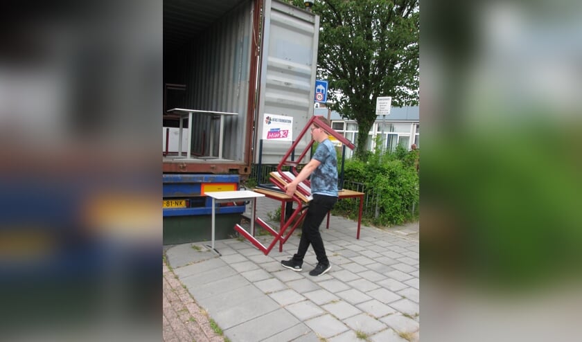Schoolmeubilair wordt in de vrachtcontainer geladen.