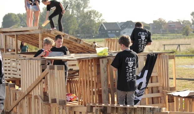 <p>Jongeren zijn druk bezig met het bouwen van een dorp van pallets.</p>