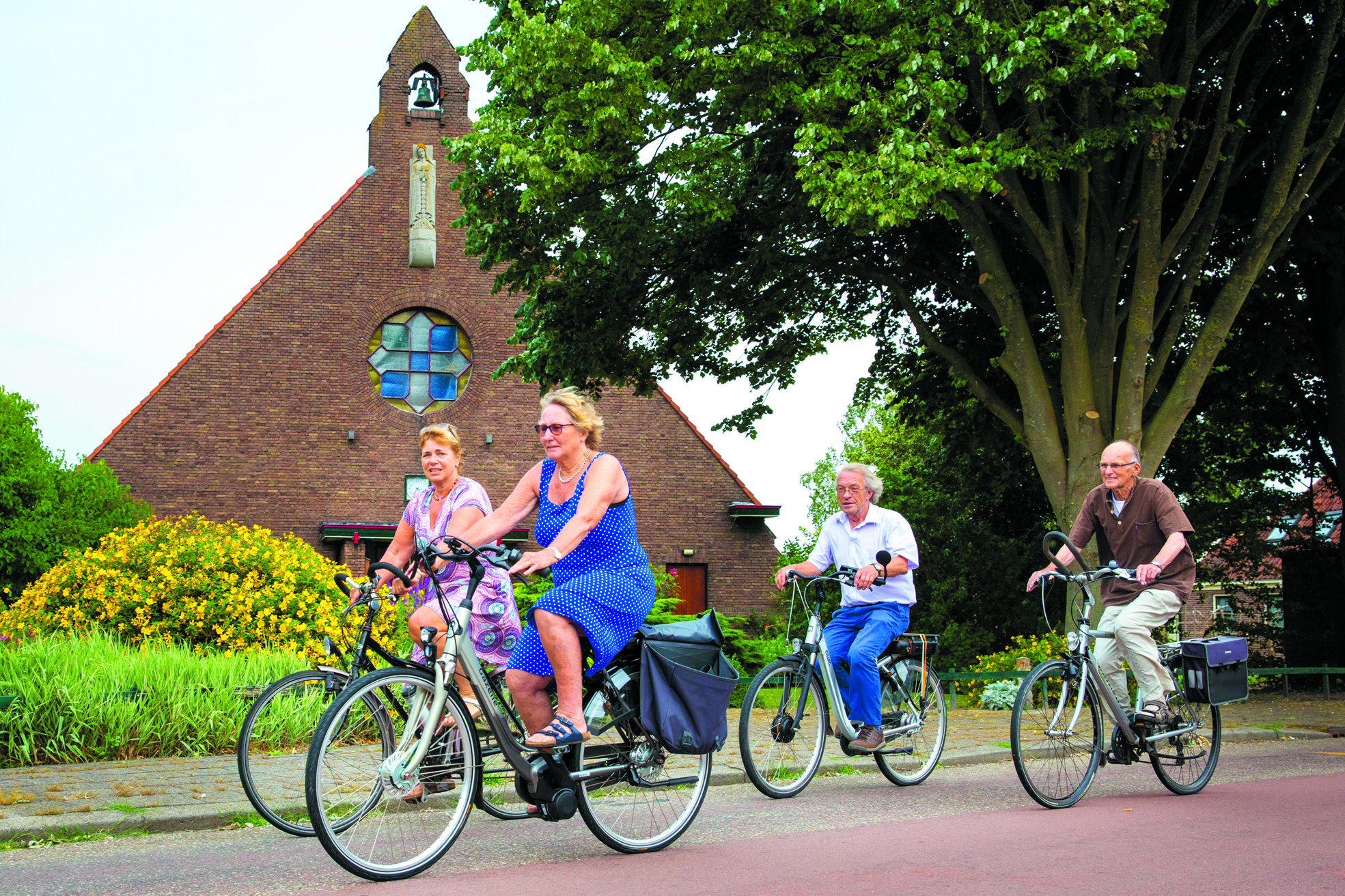 Loes Siedenburg, Lies van der Spek, Gerard van der Vliet en Jaap Visser (v.l.n.r.) van Drechterland Mondiaal fietsen langs de Theresiakapel in Hem, een van de deelnemende kerkjes. (archieffoto Vincent de Vries/RM)