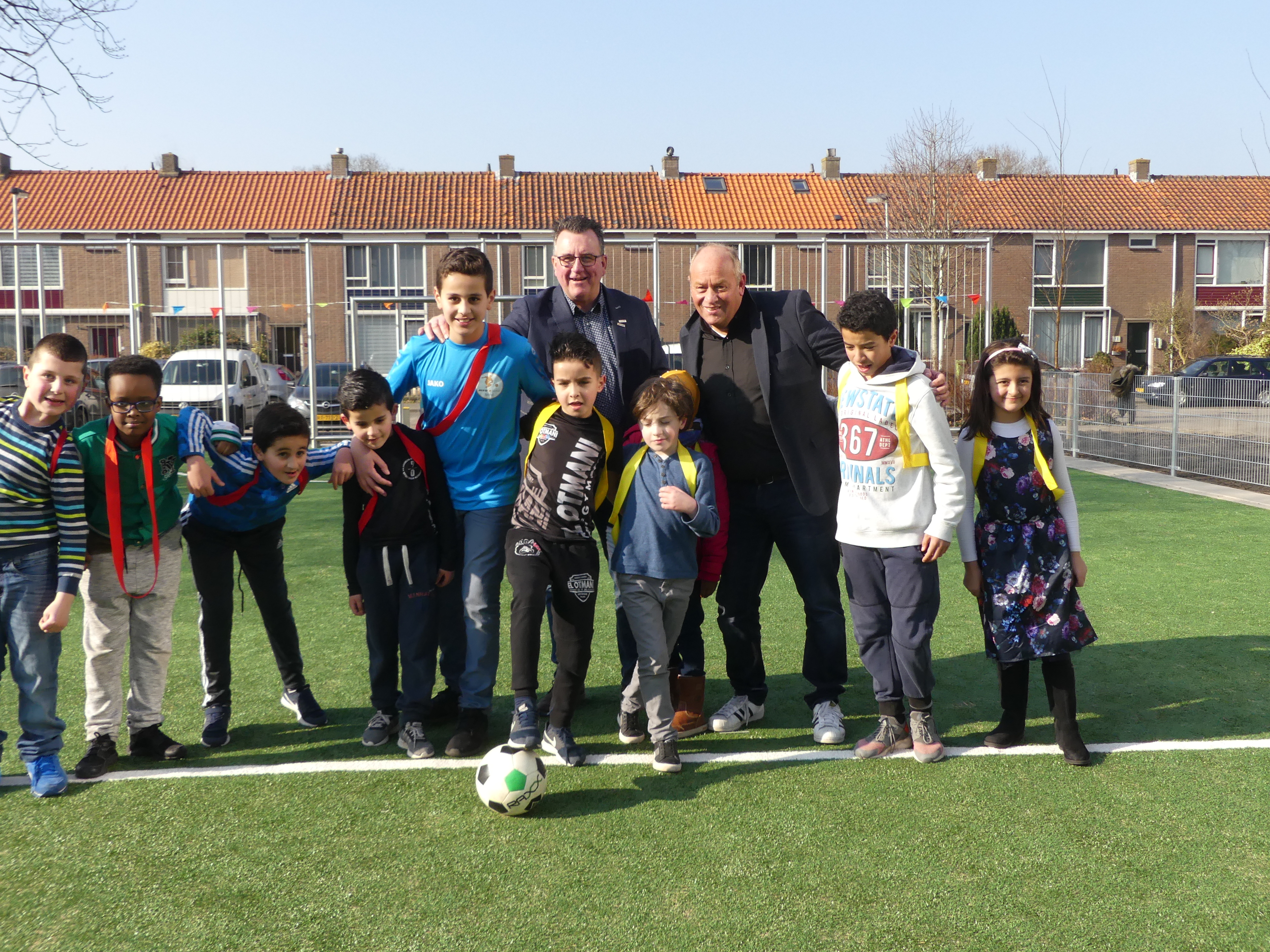 Wethouder Mario Hegger en wijkmanager Edwin Färber temidden van de jeugd op het vernieuwde veld. (Foto: Cees Bandt)