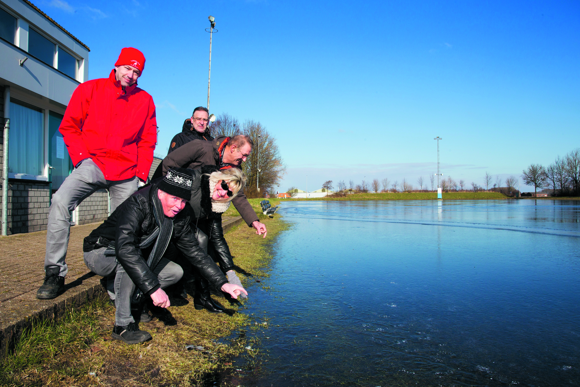 Arjan Mak (l) checkte afgelopen maandag - samen met een aantal nieuwsgierigen - het ijs van de ijsbaan in Hoogkarspel. (Foto: Vincent de Vries/RM)