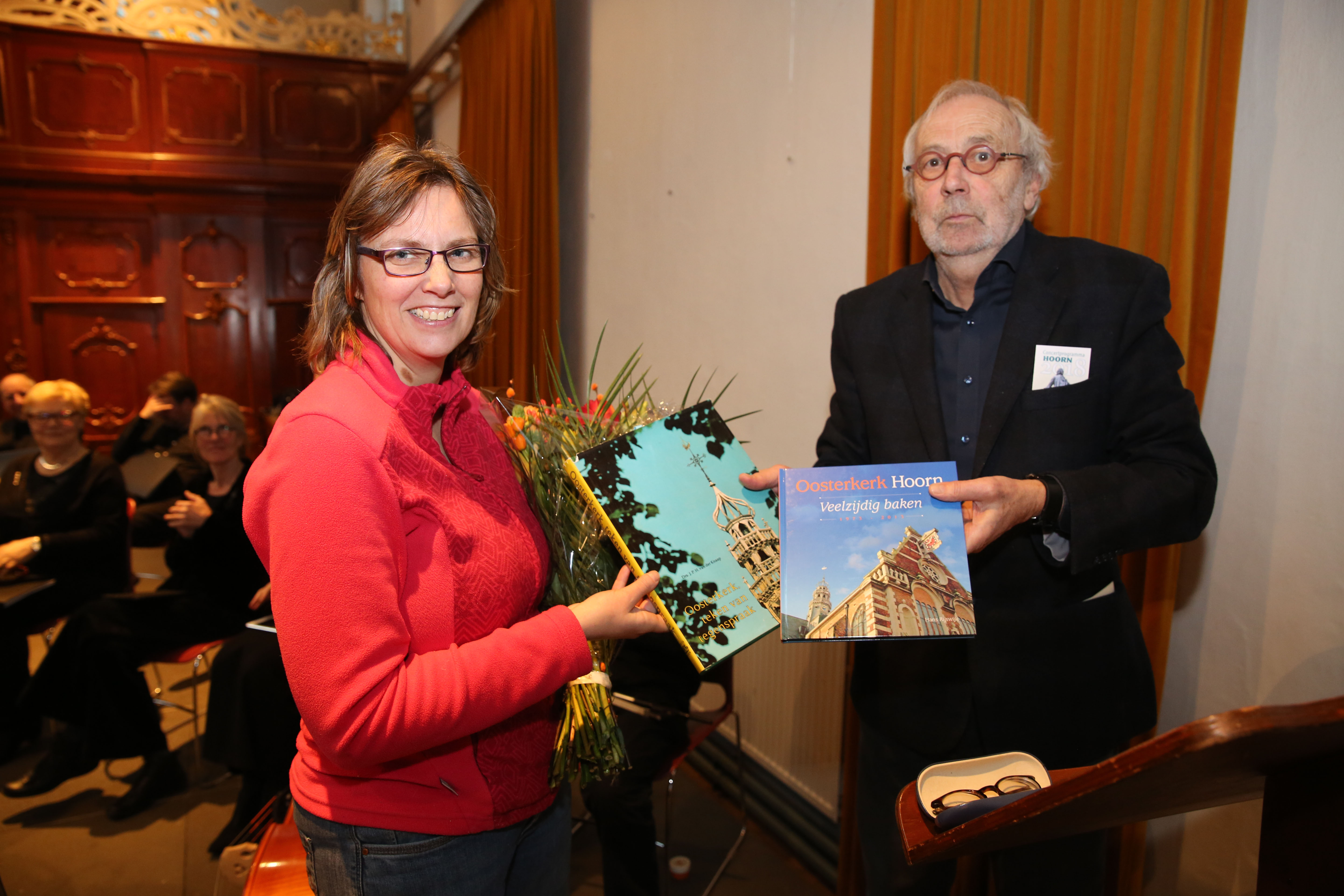 Anyal Derksen uit Elspeet (l) wordt door voorzitter Eddy Boom in het zonnetje gezet als 700.000e bezoeker van de Oosterkerk. (Foto: Theo Annes)