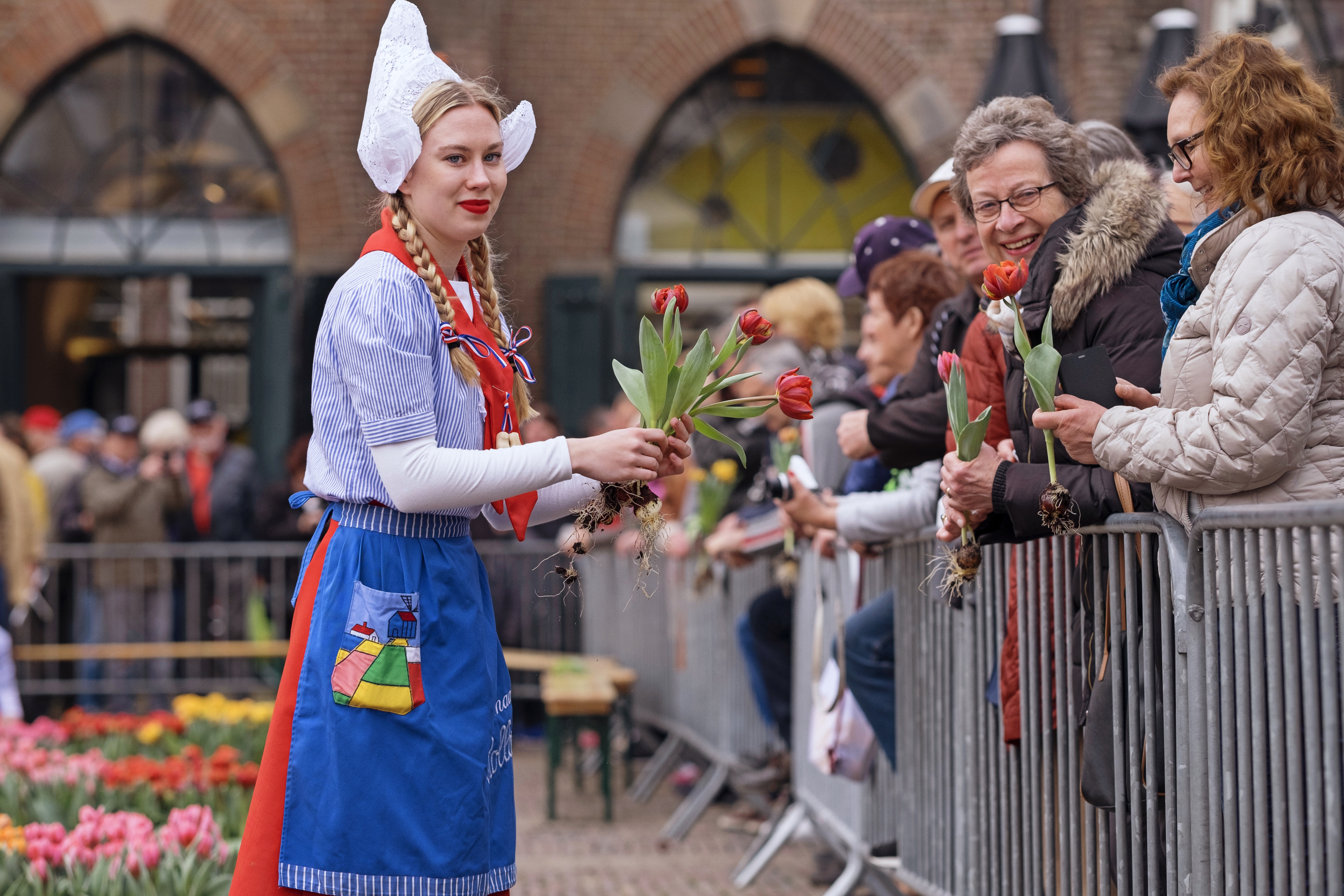 Kaasmeisjes delen tulpen uit aan bezoekers kaasmarkt. (Foto: aangeleverd)