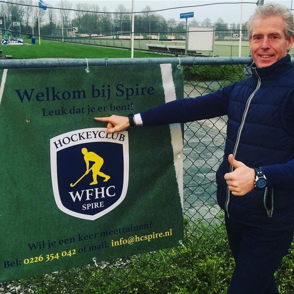 Voorzitter Gerard Welling voor de nieuwe banner bij de ingang van hockeyvereniging Spire. (Foto: aangeleverd)