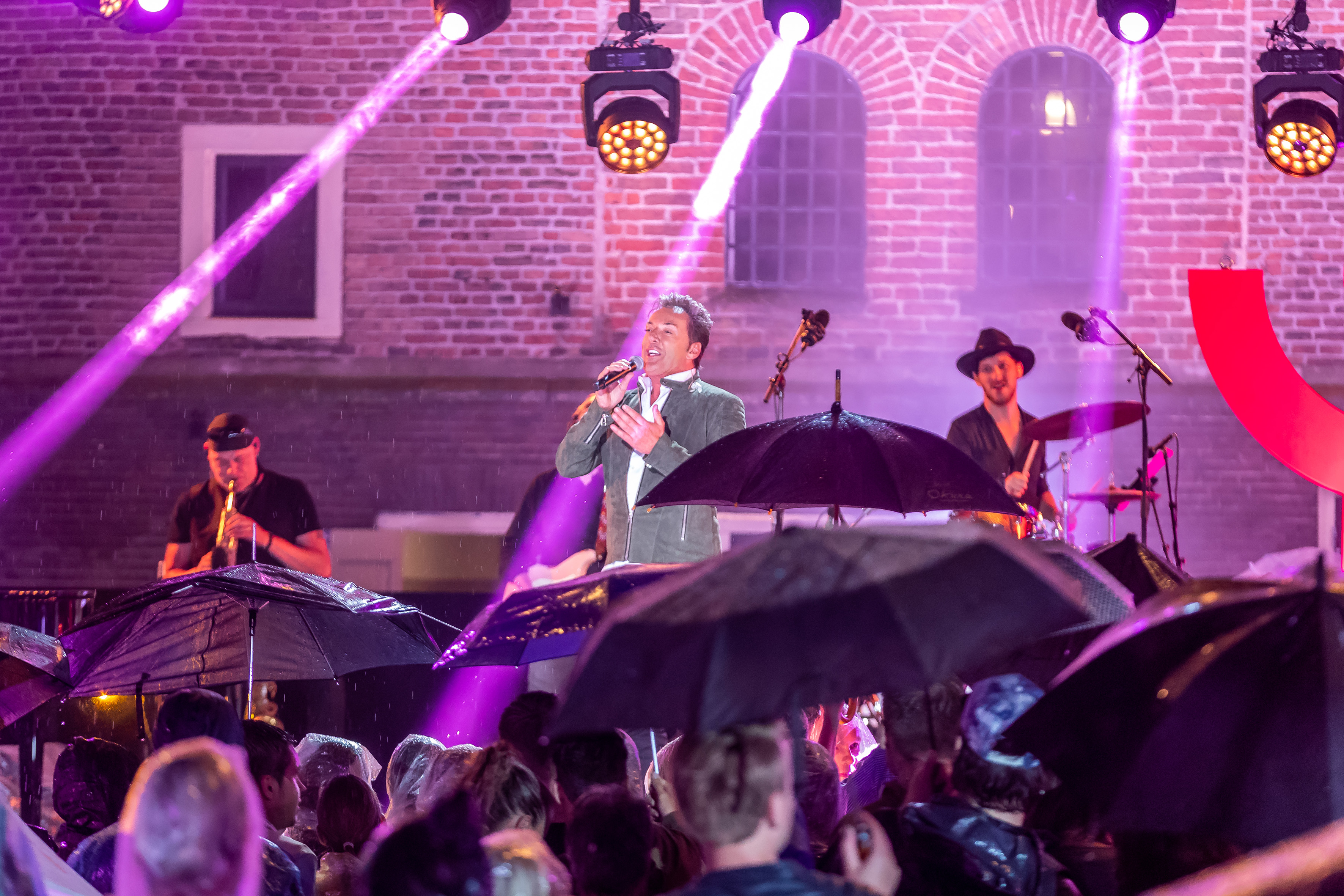 Boven de paraplu's treedt Gerard Joling op in 'Nederland staat op tegen kanker'. (Foto: Ed vd Pol)