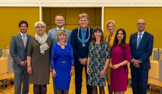 V.l.n.r.: Gerard Ram (VVD), Rita Noordzij (ChristenUnie), Gerard Slegers (CDA), Sanna Munnikendam (D66), burgemeester Jan Hamming, Natasja Groothuismink (ROSA), gemeentesecretaris Cis Apeldoorn, Songül Mutluer (PvdA) en Hans Krieger (VVD). (Foto: Bart Homburg)