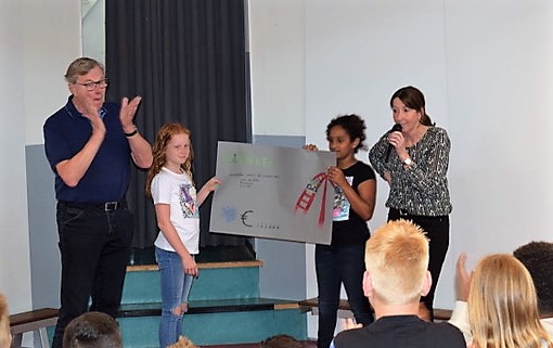 Twee leerlingen van groep 7, Jill van Braam en Janet Bendiboune, overhandigen de cheque aan Harry Jonk van Stichting Opkikker. De heer Jonk was zichtbaar ontroerd met dit mooie bedrag. (Foto: OBS De Delta)