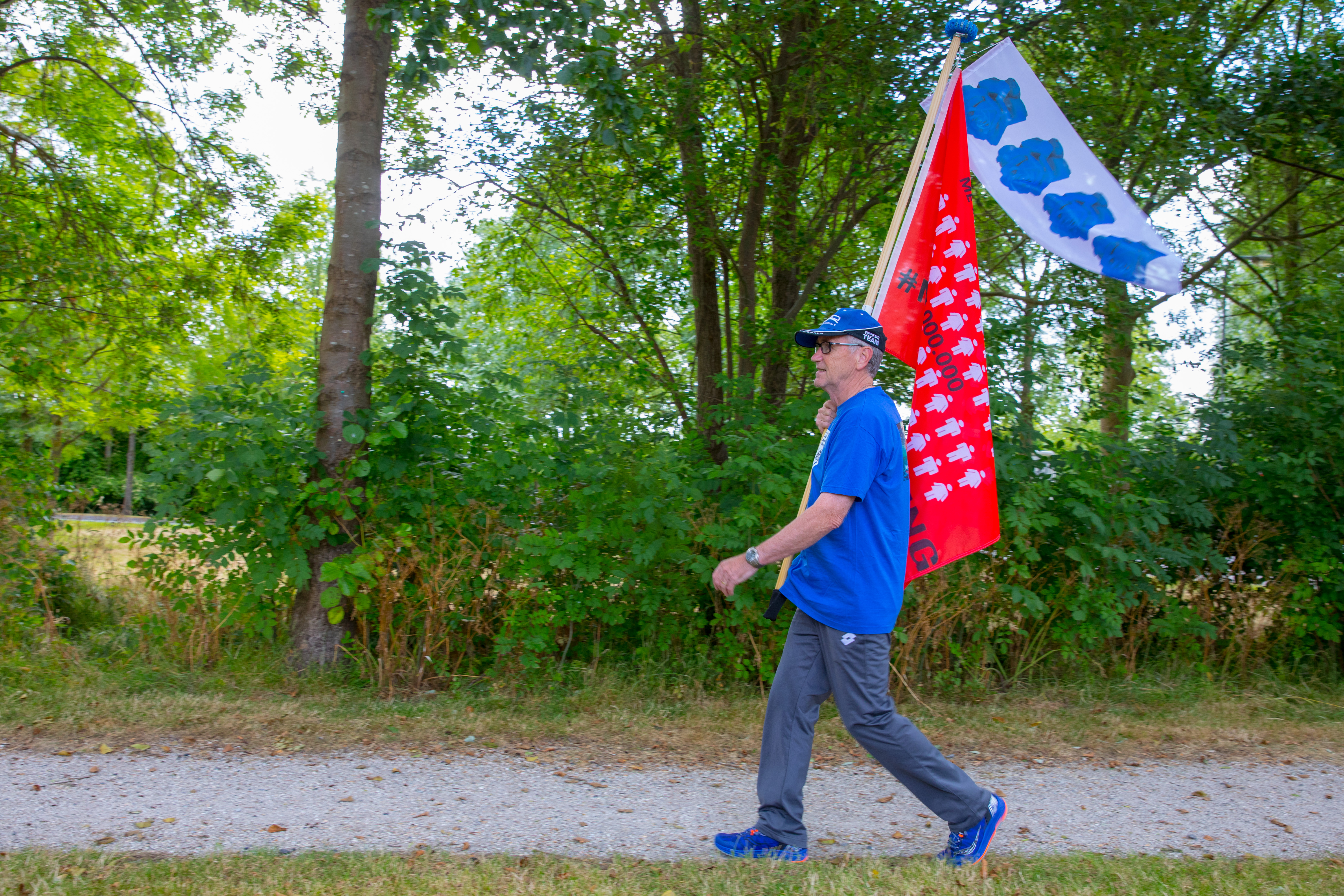 René Robert loopt tijdens de Nijmeegse Vierdaagse mét de Millions Missing-vlag: "Ik wil zoveel mogelijk aandacht vragen en geld ophalen voor de ziekte ME." (Foto: Vincent de Vries/RM)