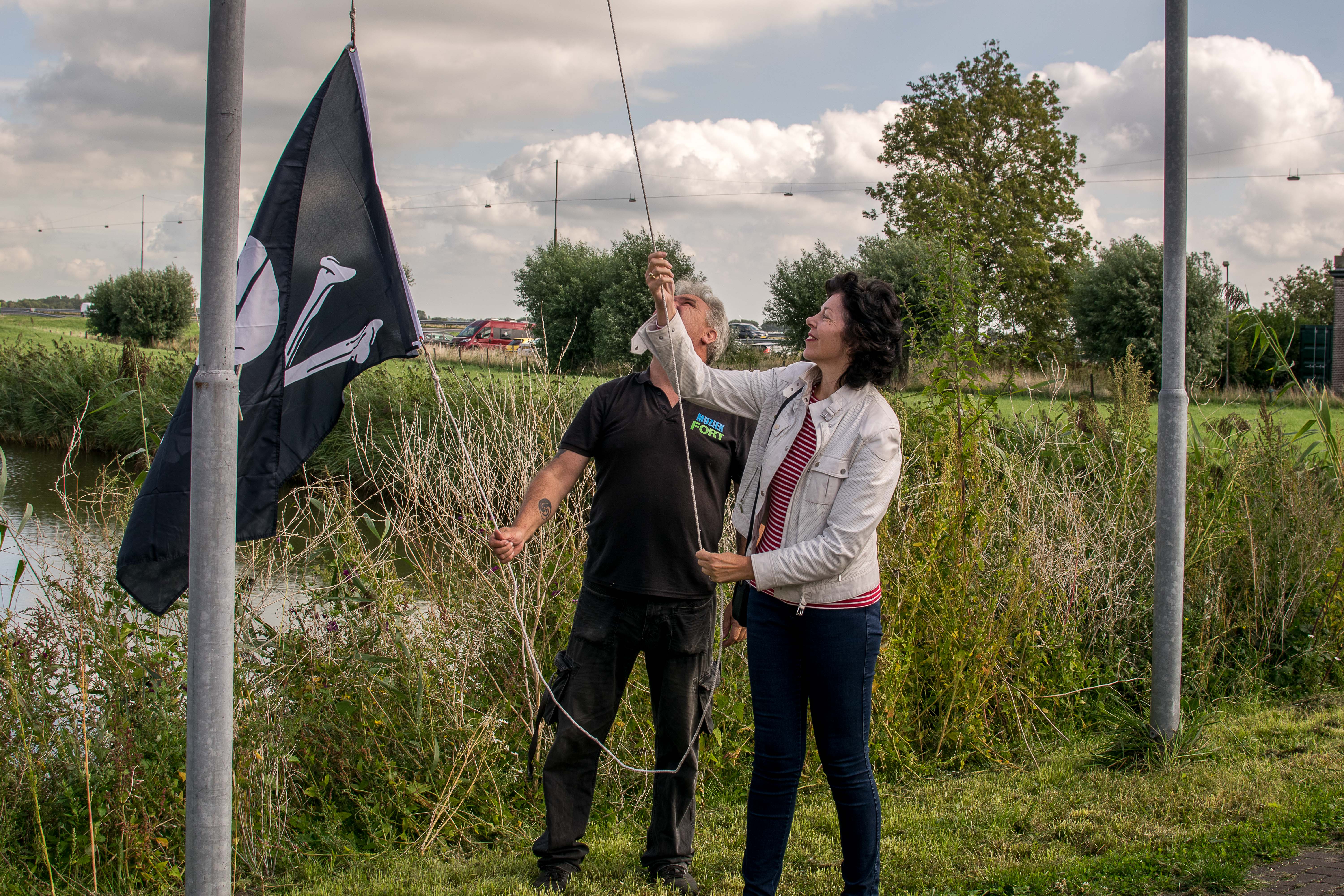 Wethouder Hanneke Niele helpt met het hijsen van de piratenvlag. (Foto: Aangeleverd)