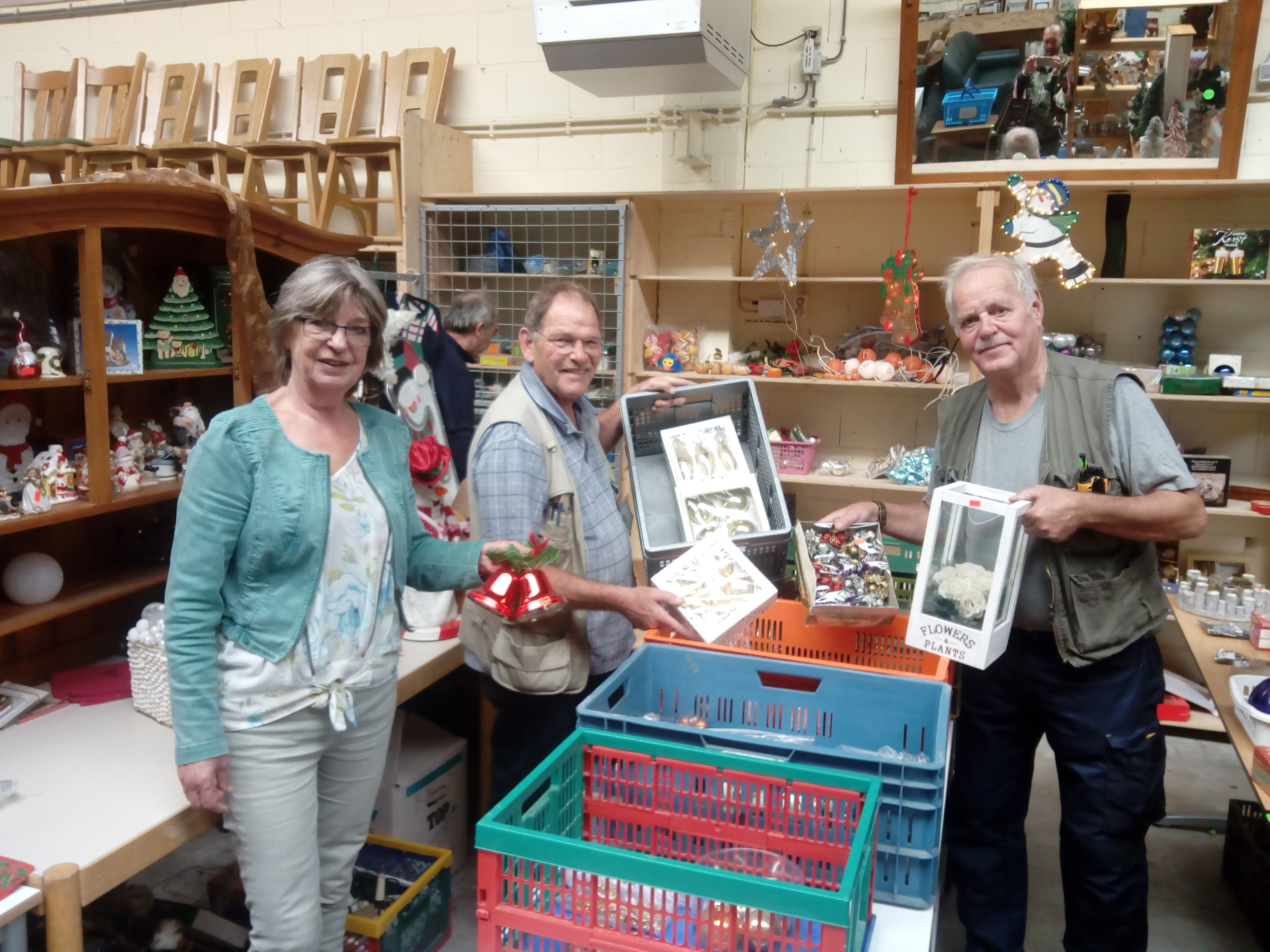 Bedrijfsleider Tineke Fraij-Stalknecht met vrijwilligers Jan van Krimpen en Jaap Vermeij op de afdeling kerstartikelen, die al in september werd ingericht. Maar liefst tweehonderd dozen vol kerstspullen had de winkel op dat moment in voorraad. (FOTO: BOS MEDIA SERVICES)