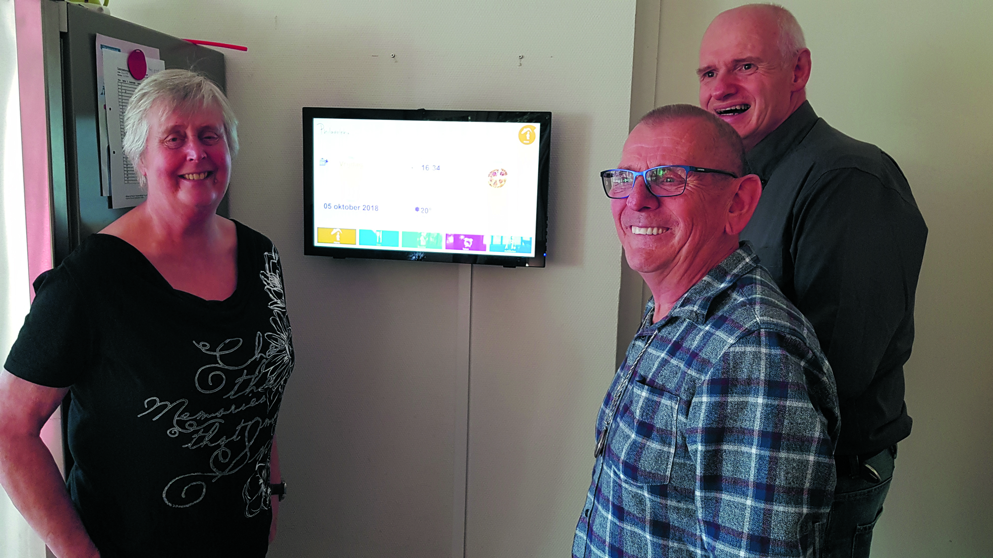 De bewoners Marjan, Gerrit en Pieter (vlnr) zijn inmiddels gewend aan het digitale bord. (foto Rodi Media)