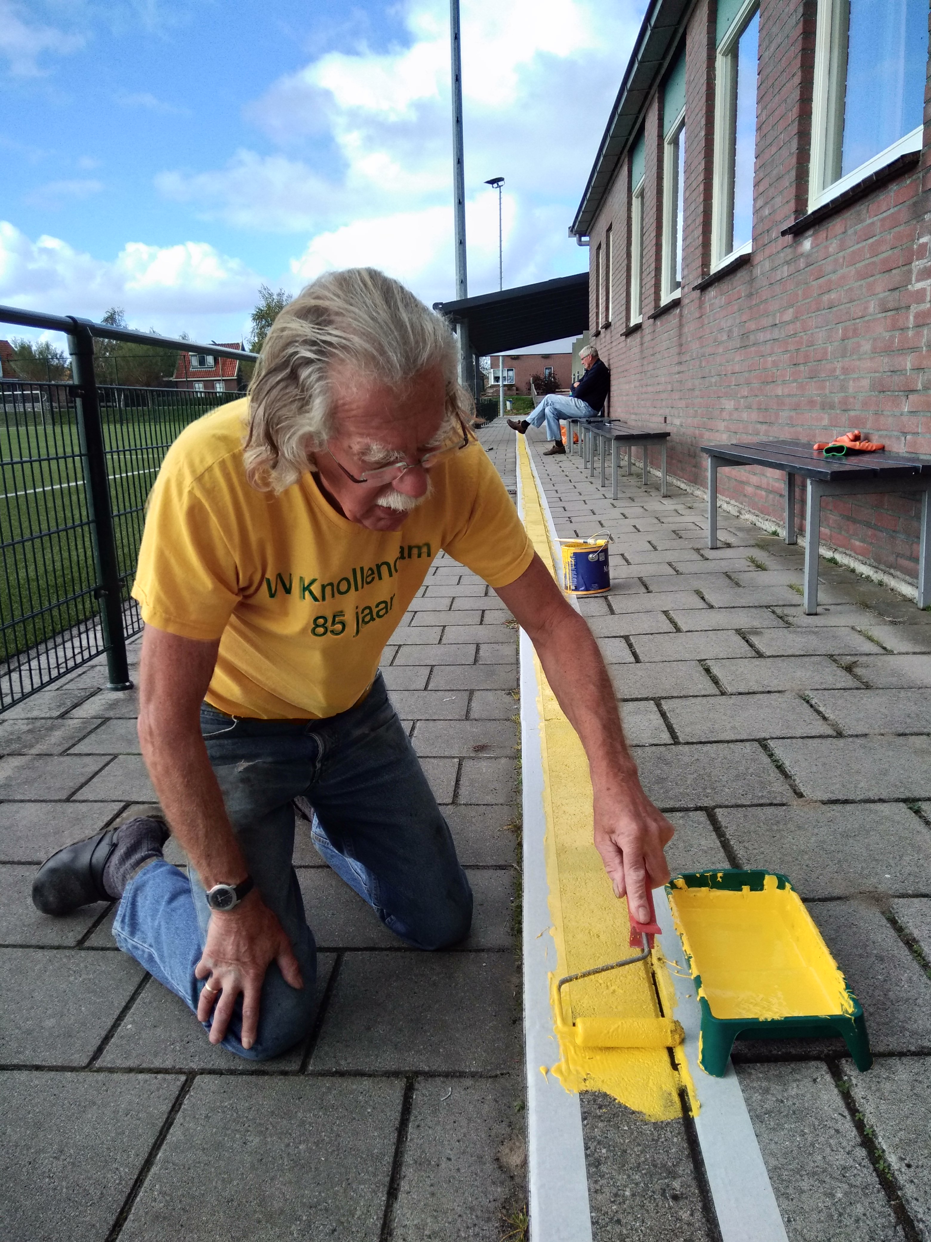 Erelid Jaap Leegwater bezig met het schilderen van een gele lijn bij vv Knollendam. (Foto: Bart van der Laan)
