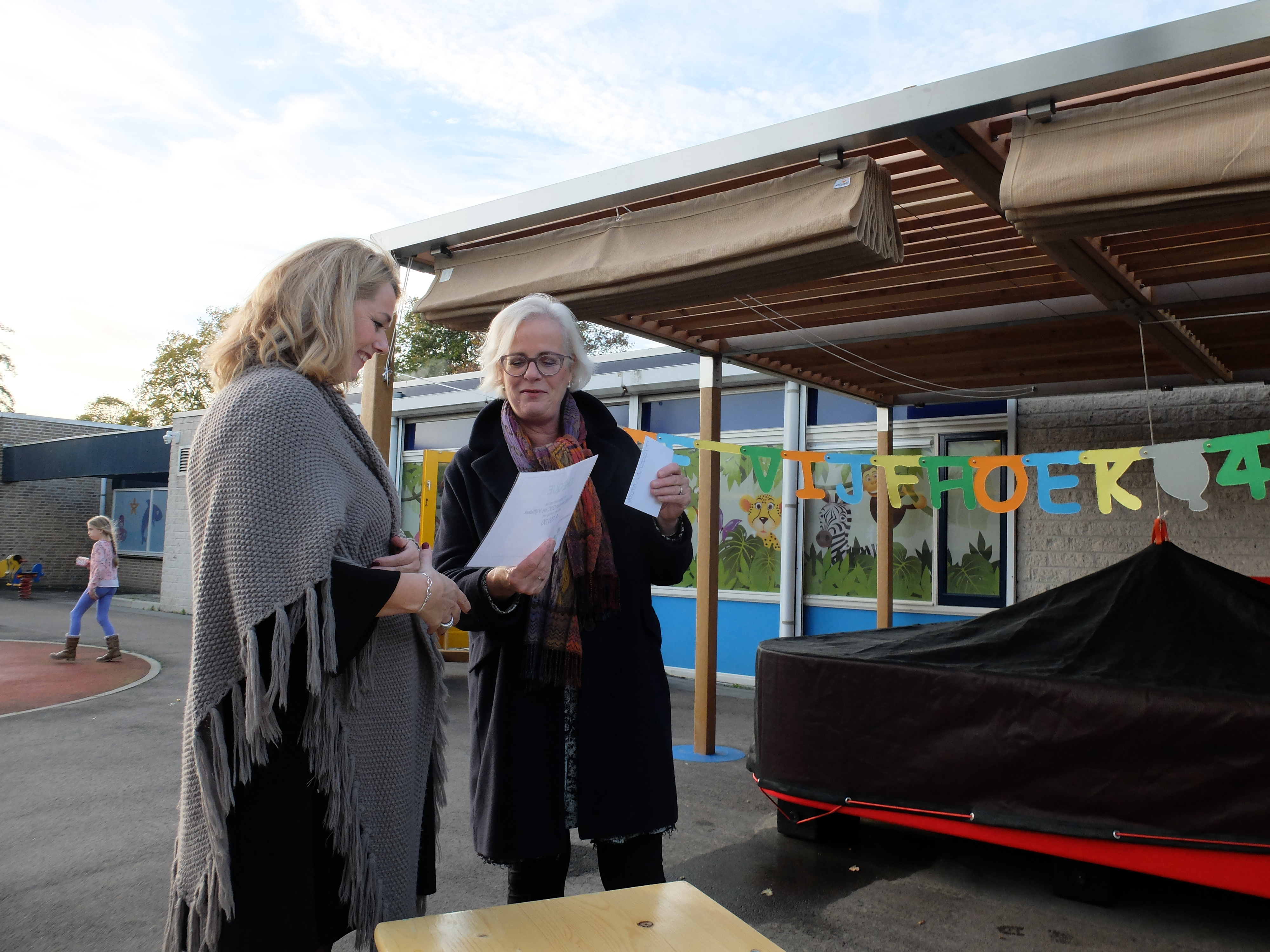 Teamleider Angelique Besseling van De Waerden (l) ontvangt een jubileumcadeau namens de gemeente Heiloo van wethouder jeugdzorg Elly Beens. (Foto: aangeleverd)