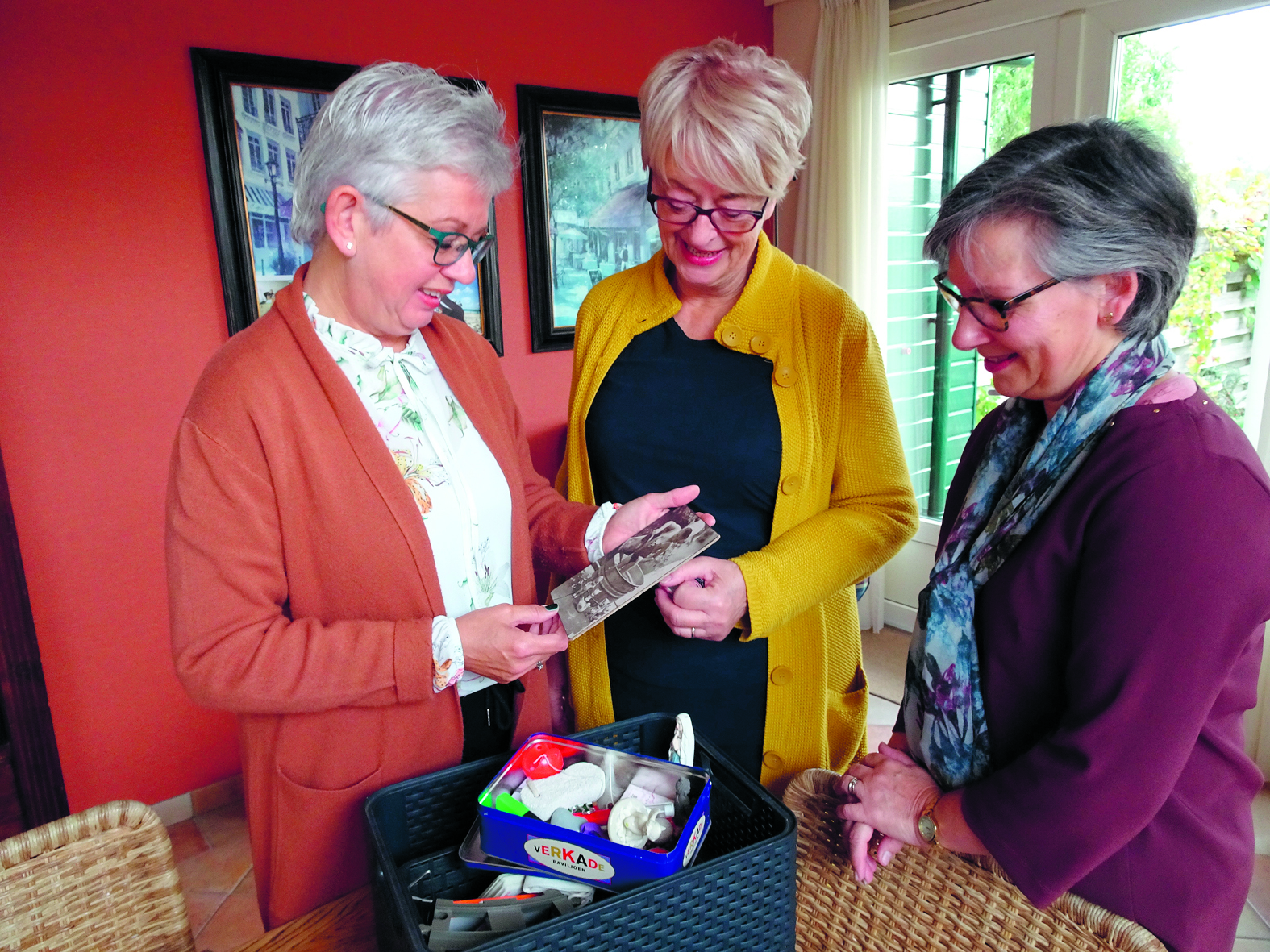 Yvonne Heddes (l), Mia Koelemeijer en Karin van ’t Klooster (r) bekijken samen herinneringen. (Foto: aangeleverd)