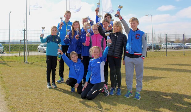 De jonge prijswinnaars van Voorne Atletiek bijeen met de behaalde trofeën.