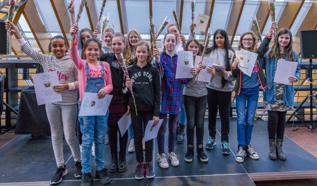 Lisa Harmeling, tweede van rechts en Neha Lovji , derde van rechts, mogen zich de lokale voorleeskampioenen noemen.