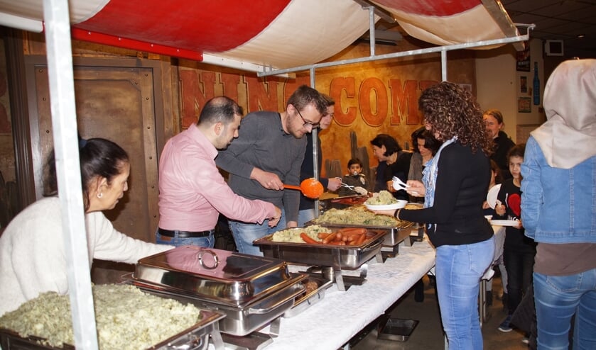 Het eten werd verzorgd door Hussam Karkas (in roze overhemd) met zijn vrouw, die drie jaar geleden vanuit Syrië naar Nederland kwamen. Hij gaat trouwens aan de slag als kok in het restaurant van WSW Ouddorp.