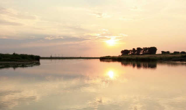 Varen in de schemering rond het natuureiland Tiengemeten. De zon zien wegzakken boven het weerspiegelende water.