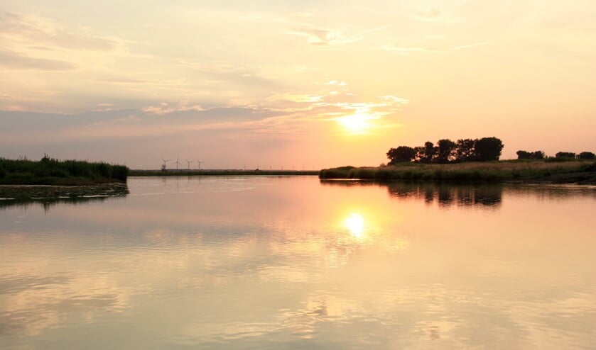 Varen in de schemering rond het natuureiland Tiengemeten. De zon zien wegzakken boven het weerspiegelende water.