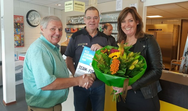 Henk van den Biggelaar (midden) en accommodatiemanager Johan de Koning (links) krijgen het zilveren vaantje uitgereikt van Karin Potting
