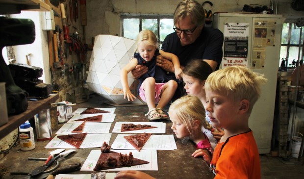 Léon Vermunt staat met de kinderen naar de net gemaakte puzzelstukjes die op de oude sok komen te staan te kijken.
