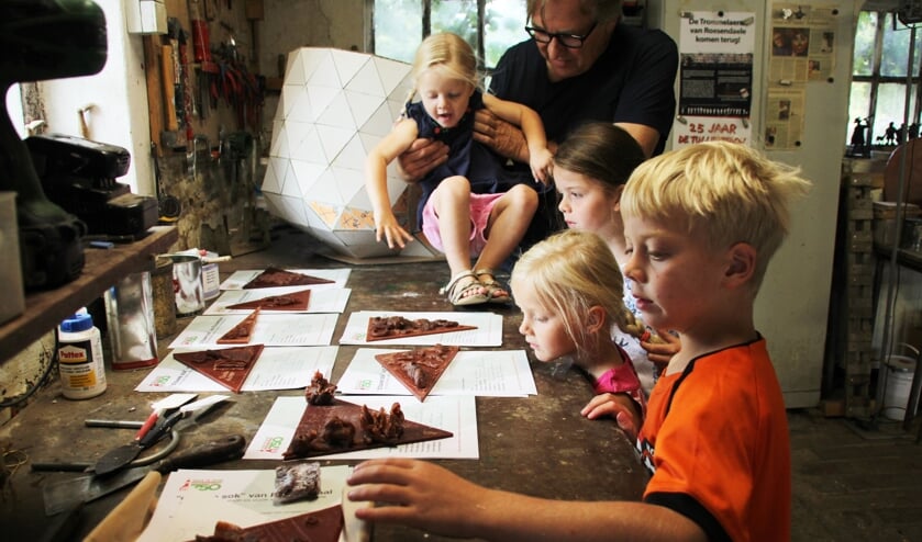 Léon Vermunt staat met de kinderen naar de net gemaakte puzzelstukjes die op de oude sok komen te staan te kijken.