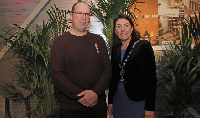 Brandweerman Mart Potter met zijn lintje en burgemeester Van Egmond met haar nieuwe ambtsketen. FOTO COBY WEIJERS