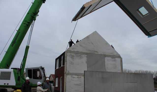 Wethouder Baartmans helpt bij het plaatsen van een dakelement op de 0 op de meter woningen aan de Lunet in Steenbergen