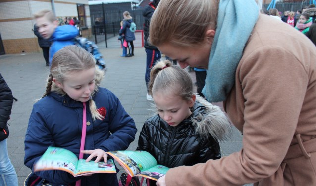 Wethouder Esther Prent neemt met een paar basisschoolleerlingen het boekje Sjors Sportief & Sjors Creatief door.