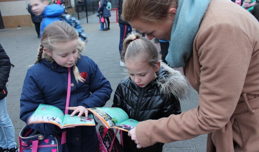 Wethouder Esther Prent neemt met een paar basisschoolleerlingen het boekje Sjors Sportief & Sjors Creatief door.