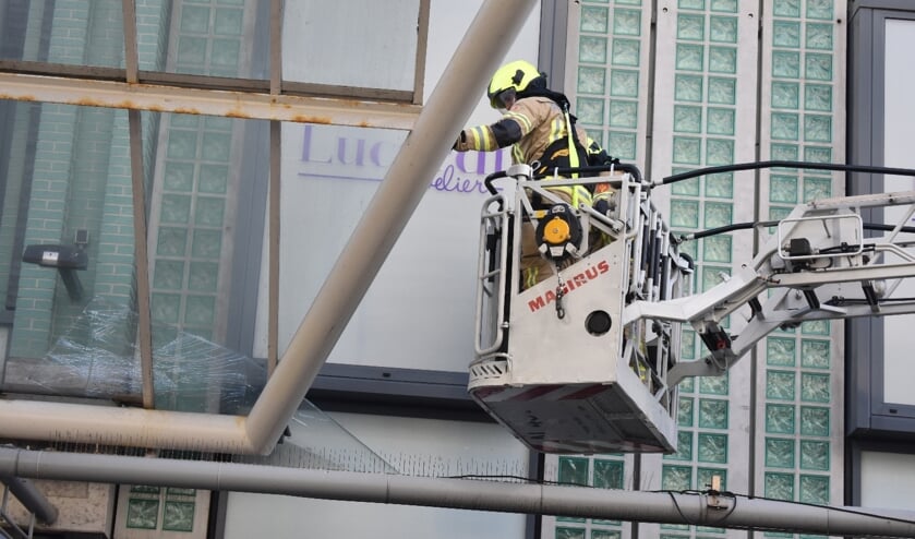 Brandweer verwijdert glasplaten boven winkelstraat 