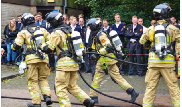Brandweerlieden kijken toe hoe collega's het incident aanpakken.