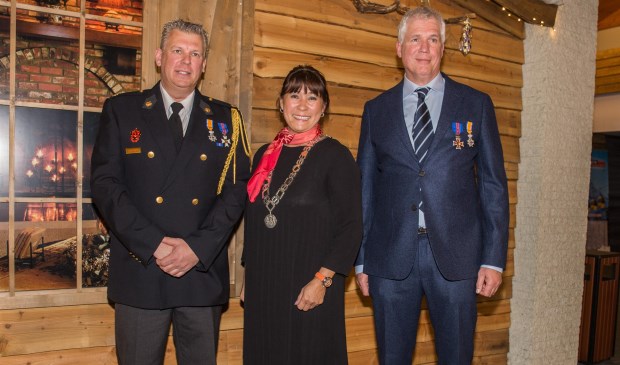 De burgemeester rijkt de lintjes uit aan de mannen.